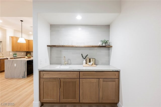 bar featuring tasteful backsplash, sink, light wood-type flooring, and decorative light fixtures