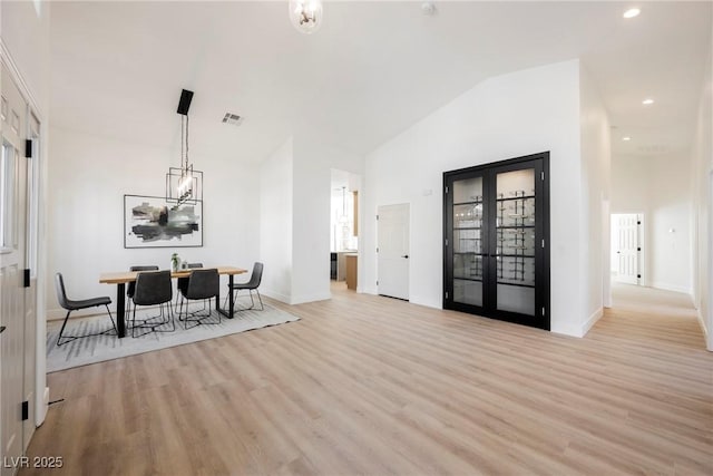 dining area with high vaulted ceiling, a chandelier, and light wood-type flooring