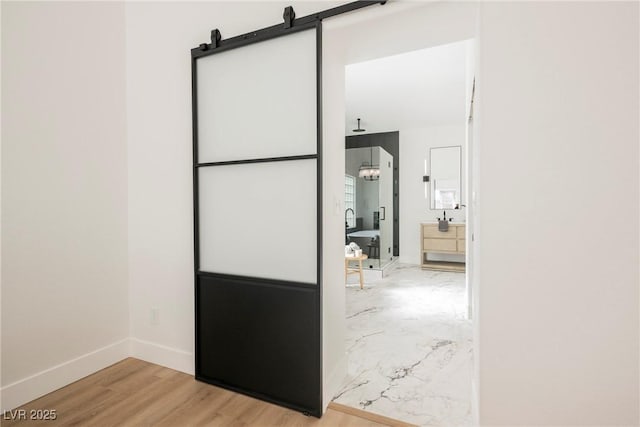 hallway with a barn door and light hardwood / wood-style floors