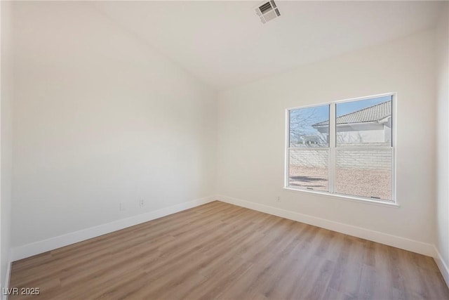 spare room with lofted ceiling and light wood-type flooring