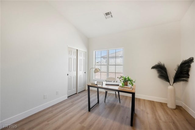 home office with high vaulted ceiling and light hardwood / wood-style flooring