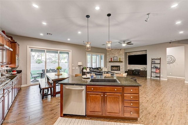 kitchen featuring light hardwood / wood-style flooring, dishwasher, dark stone counters, pendant lighting, and a center island