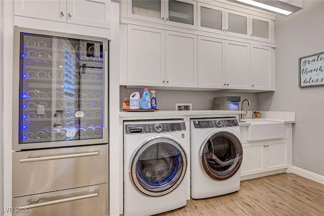 washroom featuring sink, cabinets, separate washer and dryer, and light hardwood / wood-style flooring