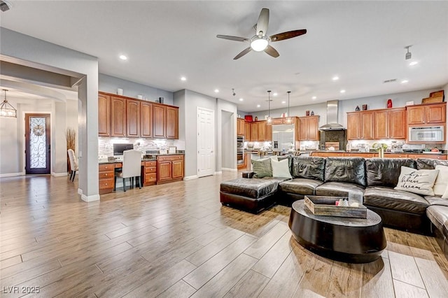 living room with ceiling fan, light wood-type flooring, and built in desk