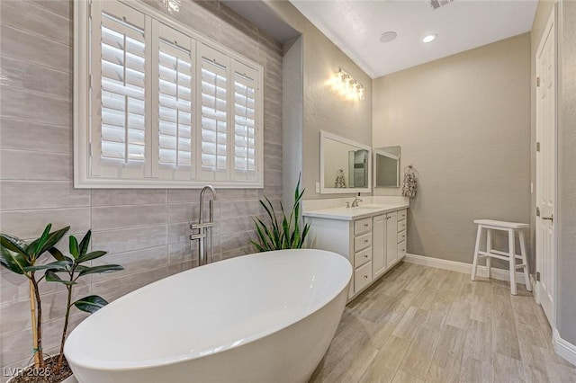 bathroom featuring hardwood / wood-style floors, a tub, and vanity