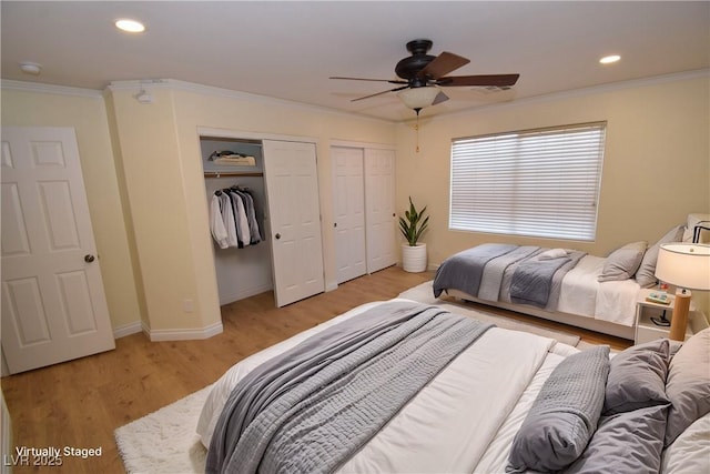 bedroom with ornamental molding, two closets, ceiling fan, and light hardwood / wood-style floors