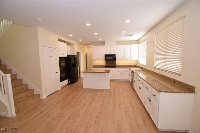 kitchen with a kitchen island, white cabinetry, dishwasher, sink, and light hardwood / wood-style floors