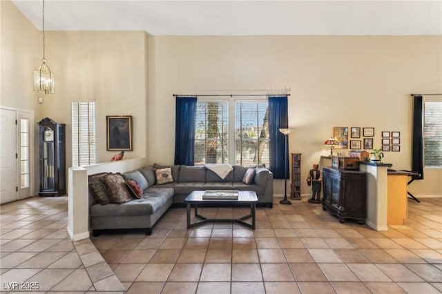 living room with a high ceiling, light tile patterned flooring, and a chandelier