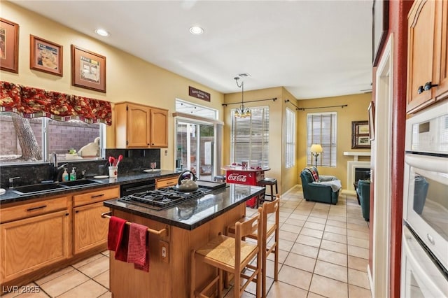 kitchen featuring sink, hanging light fixtures, a kitchen breakfast bar, stainless steel gas cooktop, and a kitchen island