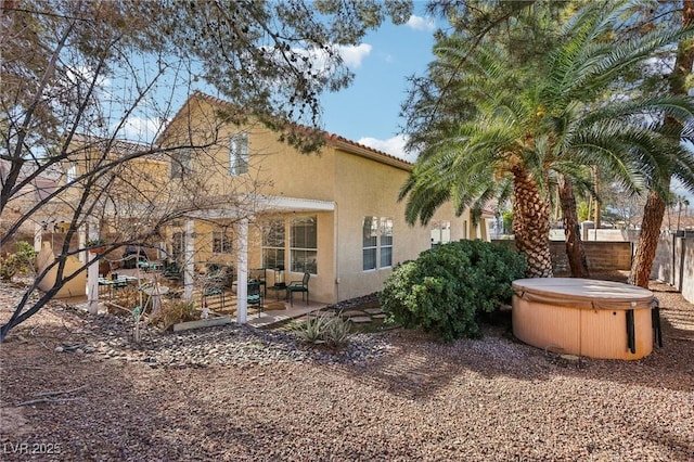 rear view of house with a hot tub and a patio