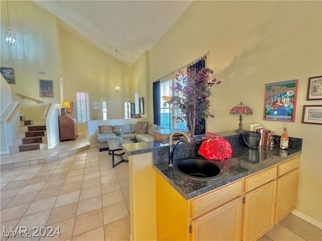 kitchen featuring sink, light tile patterned floors, high vaulted ceiling, light brown cabinetry, and kitchen peninsula