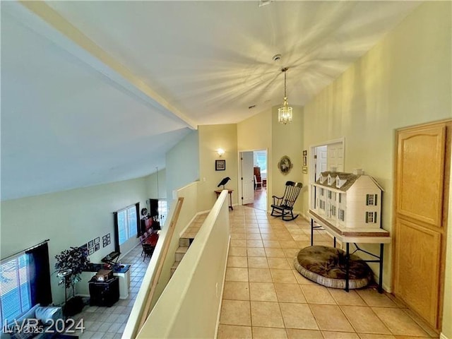 corridor featuring beamed ceiling, a notable chandelier, plenty of natural light, and light tile patterned floors