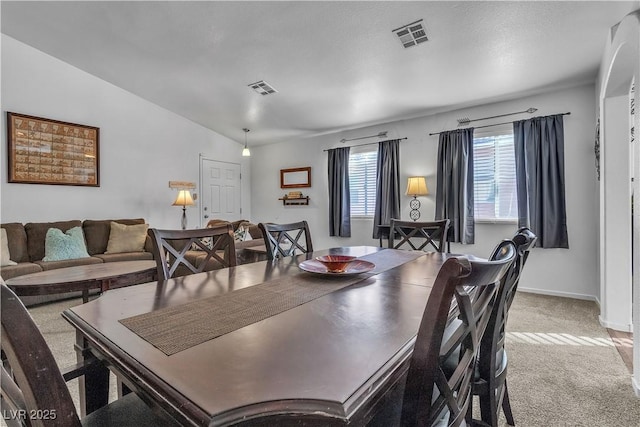 dining space featuring light carpet and vaulted ceiling