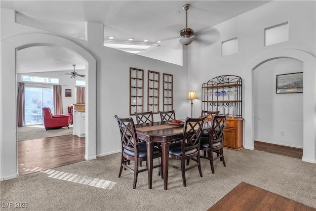 carpeted dining space featuring high vaulted ceiling and ceiling fan