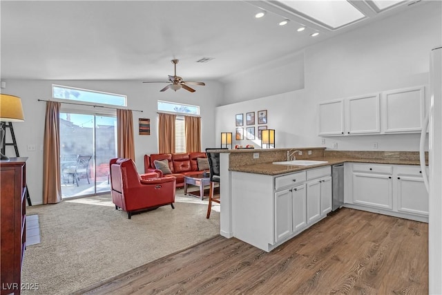 kitchen featuring vaulted ceiling, sink, white cabinets, kitchen peninsula, and light wood-type flooring