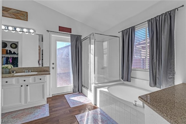 bathroom with shower with separate bathtub, vaulted ceiling, hardwood / wood-style floors, and vanity