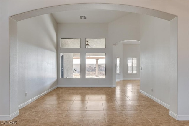 tiled spare room with a high ceiling