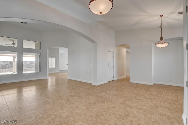 tiled empty room featuring ceiling fan and a high ceiling