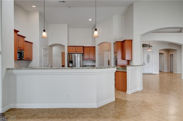 kitchen with light stone counters, appliances with stainless steel finishes, decorative light fixtures, and kitchen peninsula