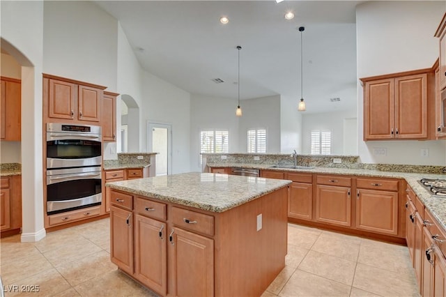 kitchen with pendant lighting, high vaulted ceiling, sink, a center island, and stainless steel appliances