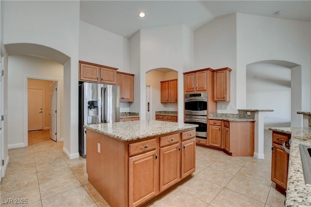 kitchen with light stone counters, light tile patterned floors, appliances with stainless steel finishes, and a kitchen island