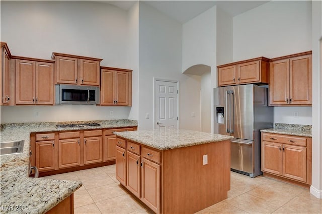 kitchen with light stone counters, stainless steel appliances, high vaulted ceiling, and a kitchen island