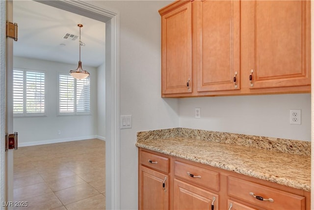 kitchen featuring pendant lighting and light stone counters