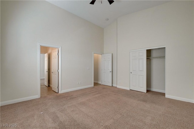 unfurnished bedroom with ceiling fan, light colored carpet, high vaulted ceiling, and a closet