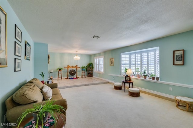 carpeted living room featuring a notable chandelier and a textured ceiling