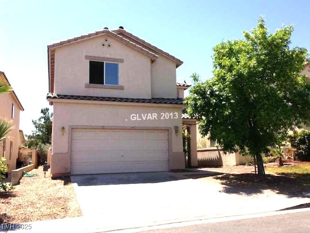 mediterranean / spanish-style house with a garage, concrete driveway, a tile roof, and stucco siding