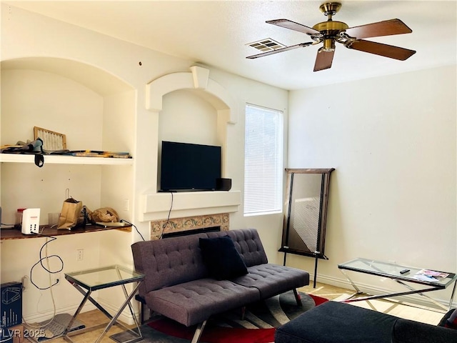 living room with ceiling fan, a fireplace, visible vents, and baseboards