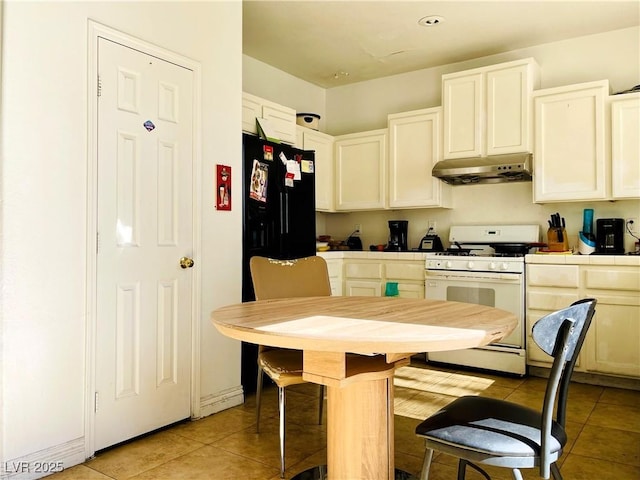 kitchen featuring light tile patterned floors, tile counters, white cabinetry, under cabinet range hood, and white gas range oven