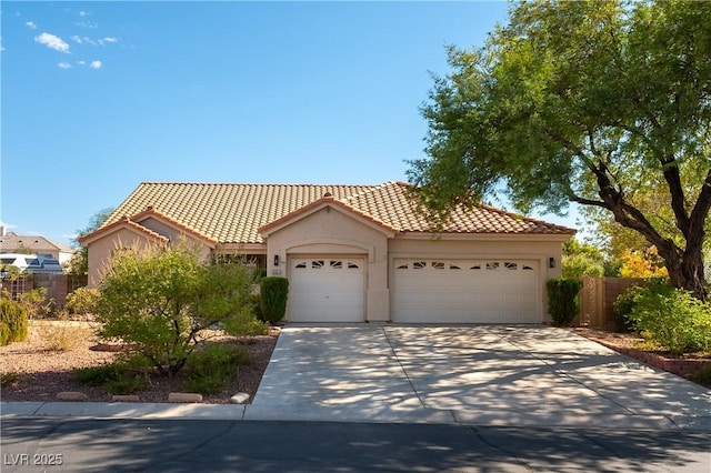 mediterranean / spanish home featuring a garage, fence, concrete driveway, a tiled roof, and stucco siding