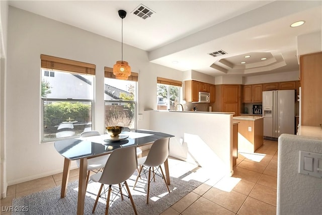 dining room featuring light tile patterned floors, a tray ceiling, visible vents, and baseboards