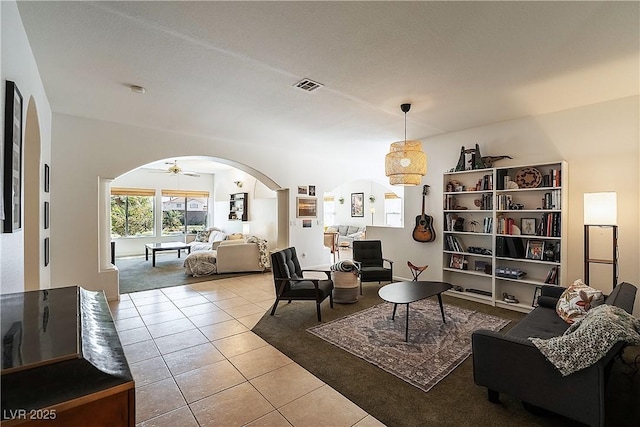 living room featuring arched walkways, ceiling fan, visible vents, and tile patterned floors