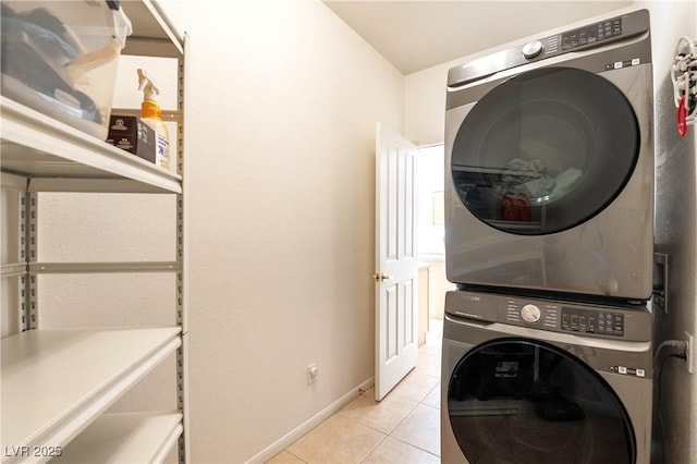 laundry area featuring laundry area, stacked washer and dryer, light tile patterned flooring, and baseboards