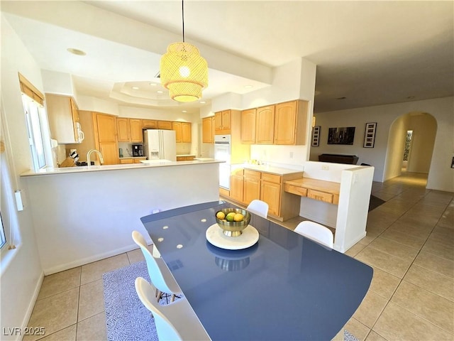 dining space featuring light tile patterned floors, baseboards, arched walkways, and a raised ceiling