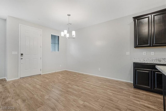 unfurnished dining area with an inviting chandelier and light hardwood / wood-style flooring