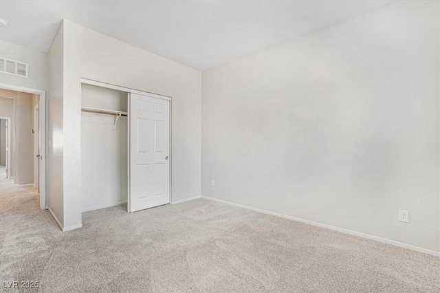 unfurnished bedroom with light colored carpet and a closet