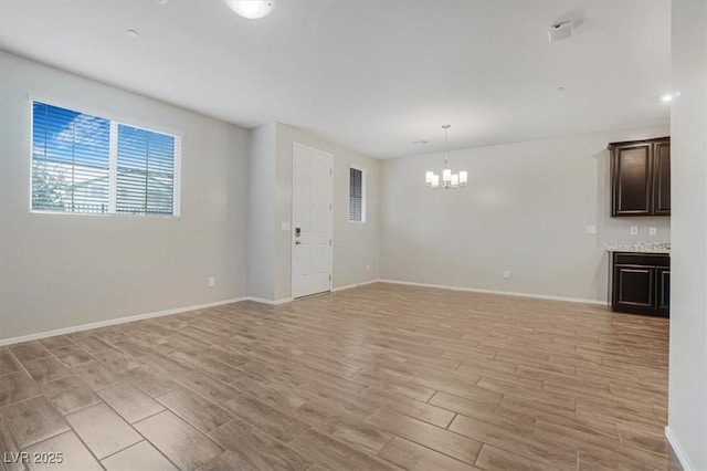 unfurnished living room with a chandelier and light hardwood / wood-style flooring