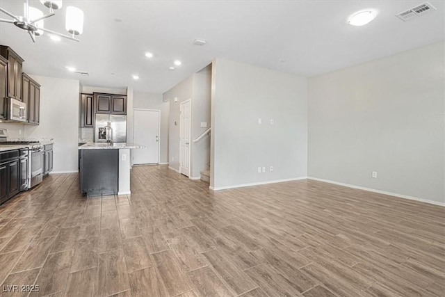 kitchen featuring hardwood / wood-style floors, dark brown cabinets, stainless steel appliances, a center island, and a notable chandelier