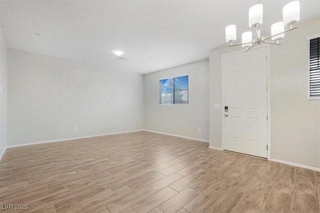 spare room with a notable chandelier and light hardwood / wood-style floors