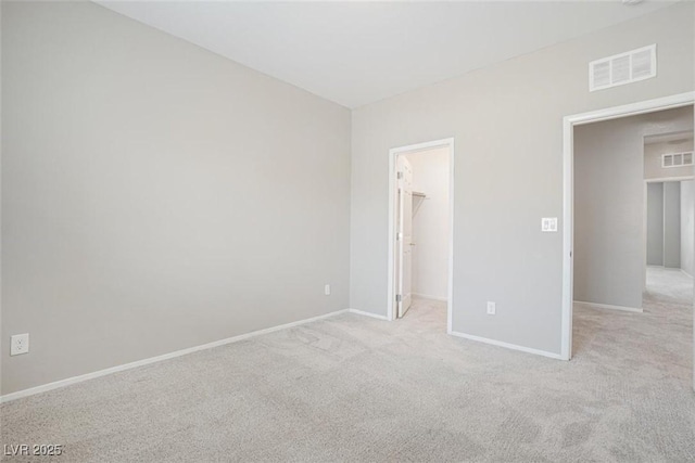 unfurnished bedroom featuring a walk in closet, light colored carpet, and a closet