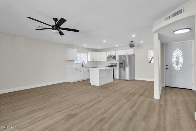 kitchen featuring a kitchen island, white cabinetry, sink, stainless steel appliances, and light hardwood / wood-style flooring