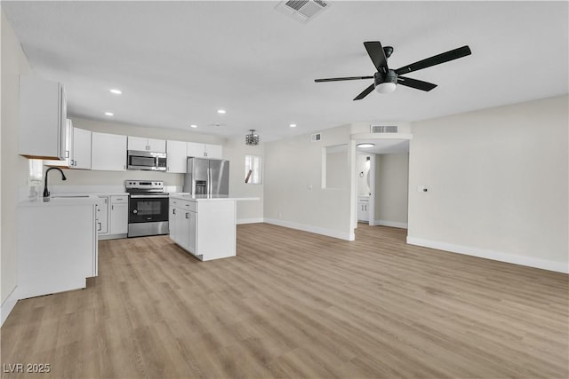 kitchen with white cabinetry, stainless steel appliances, sink, and a kitchen island