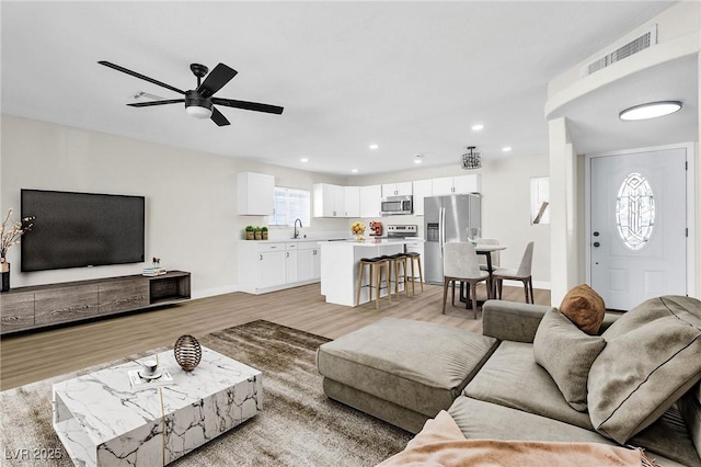 living room with sink, ceiling fan, and light hardwood / wood-style flooring