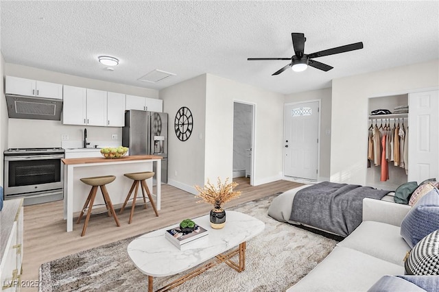 living room featuring sink, a textured ceiling, light hardwood / wood-style floors, and ceiling fan