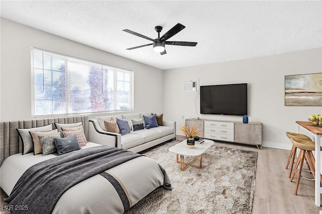 living room featuring a textured ceiling, ceiling fan, and light wood-type flooring