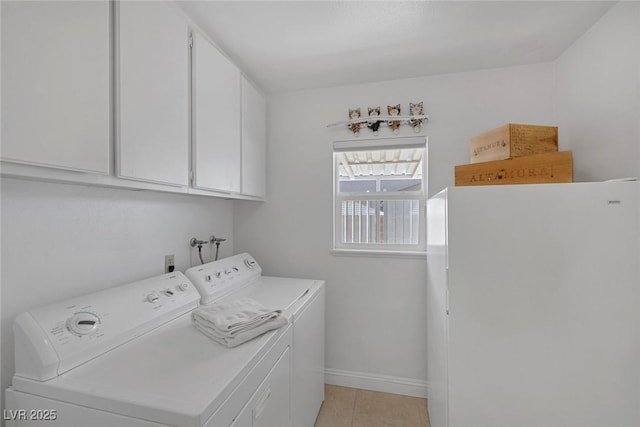 clothes washing area with cabinets, washing machine and clothes dryer, and light tile patterned flooring