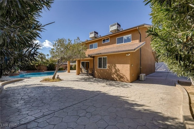 rear view of property with cooling unit and a patio